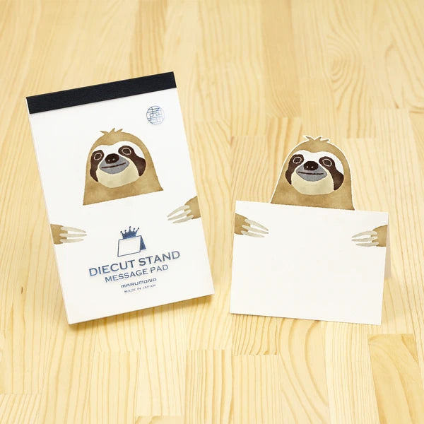 Message pad with sloth design on a wooden surface
