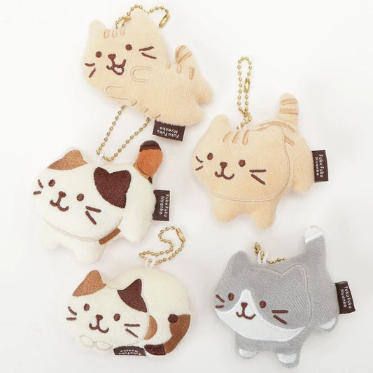 Five small plush cat keychain charms in different colors and patterns, arranged on a plain white background. Each cat charm has a gold chain loop at the top and a small black fabric tag with white text.