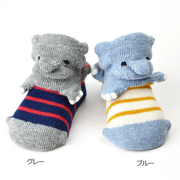 Color variation of baby socks with plush elephant foot covers, one in gray and navy with red stripes, and one in light blue and cream with yellow stripes, shown on a white background with Japanese text labels.